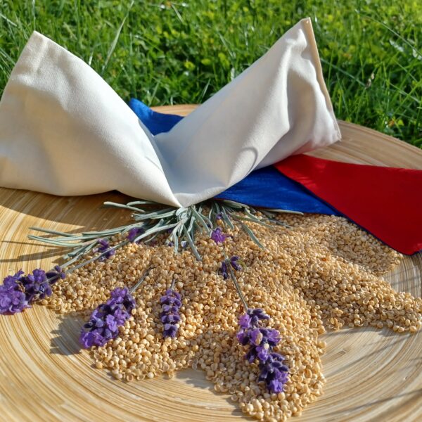 Zusehen sind ein beiges Augenkissen was auf einen kleinen Arrangement aus gewaschener Hirsespelz mit 4 kleinen Lavendelzweigen.