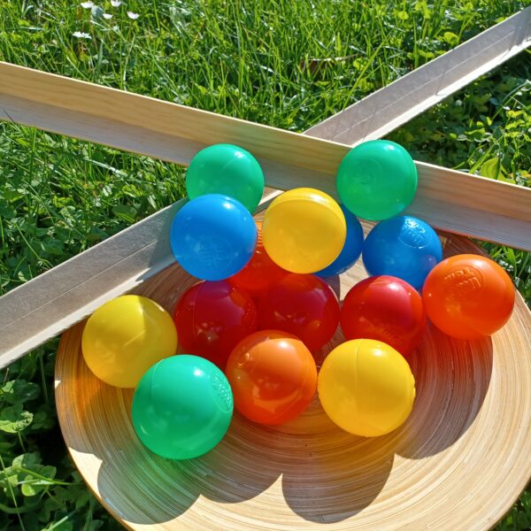 Zusehen ist ein Holzteller mit 15 farbigen Kunststoffbällen und 2 Eckleisten aus Pappe oder Holz.