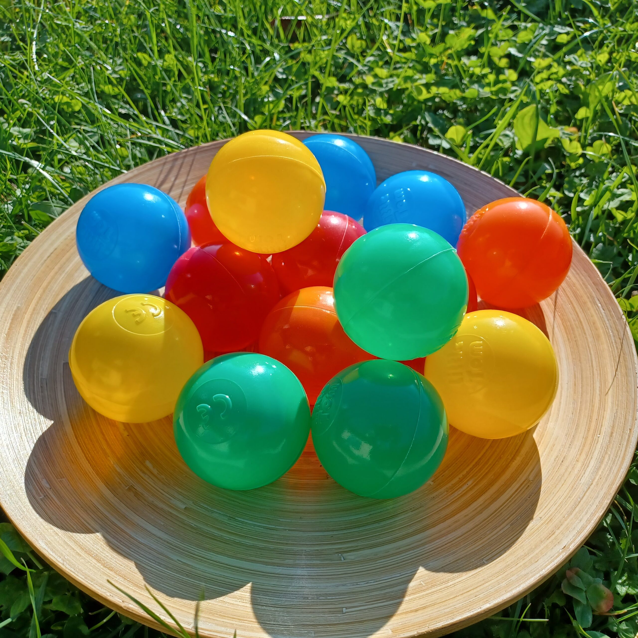 Zusehen ist ein Holzteller mit 15 farbigen Kunststoffbällen.